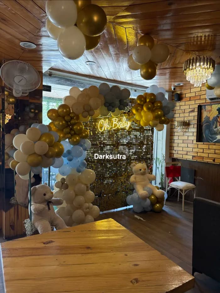 Gold sequin shimmer wall with a neon Oh Baby sign, cream and gold balloons and teddy bears