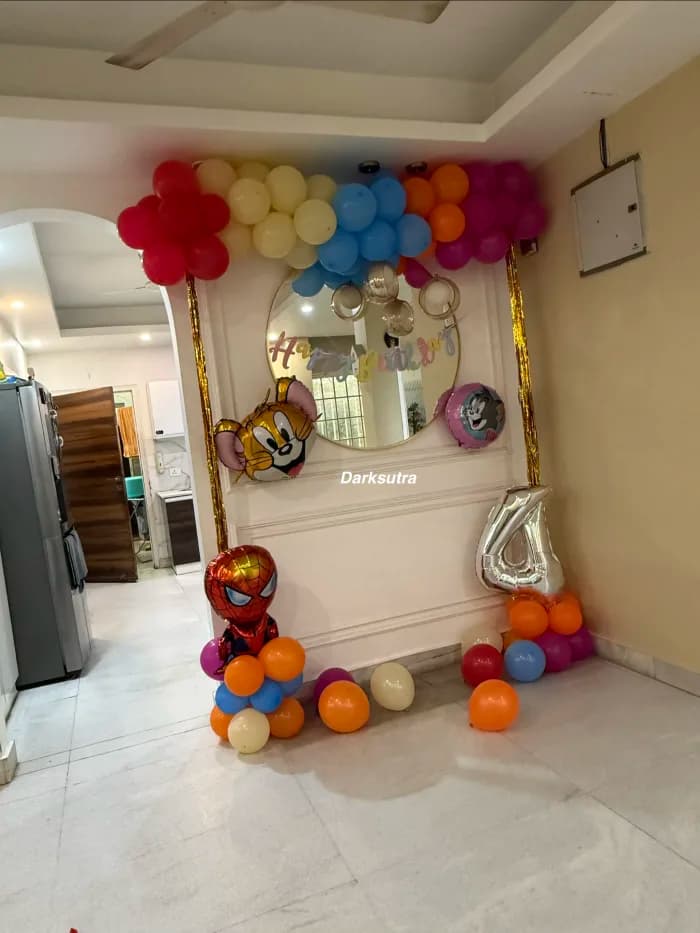 Cartoon themed balloon arch in red, cream and orange around a round mirror with a silver number four