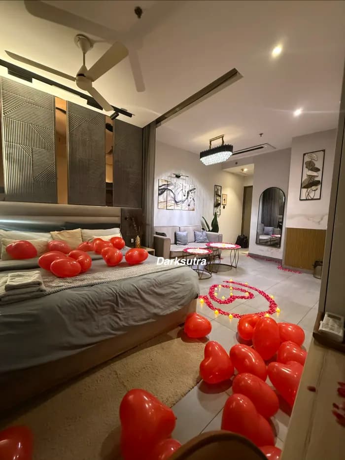 Bedroom and living area filled with red heart balloons and a rose petal heart on the floor