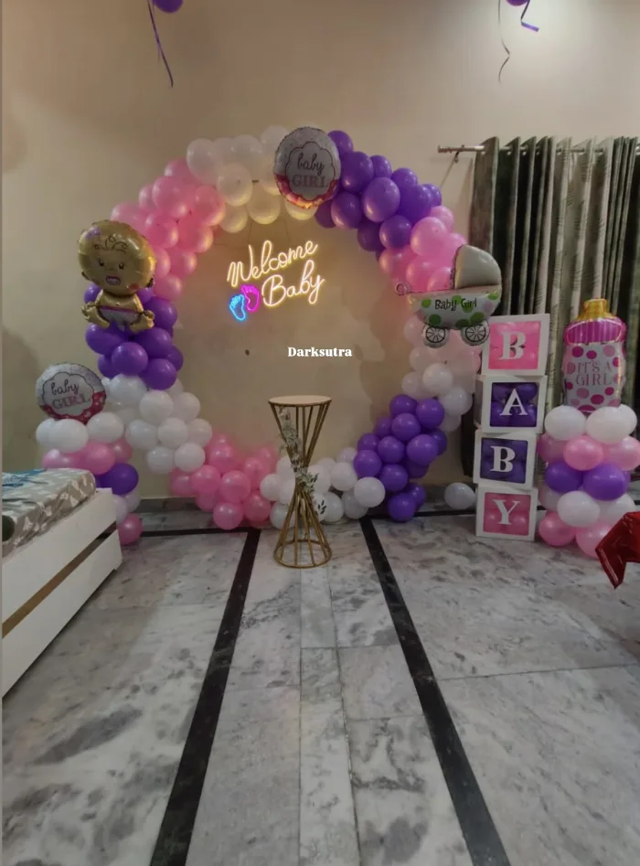 Pink, purple and white balloon ring arch with a neon Welcome Baby sign, baby foil balloons and BABY blocks