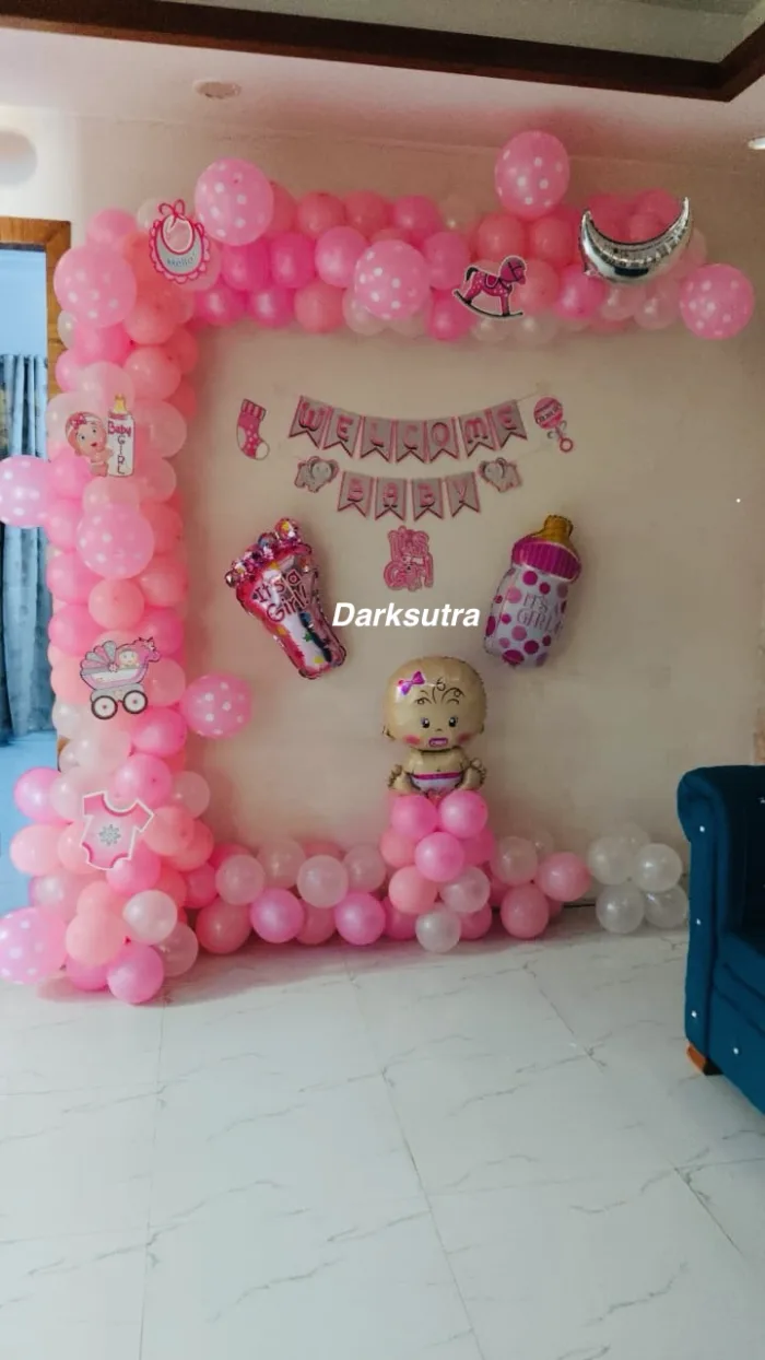 Pink balloon frame with a Welcome Baby banner, pram, rattle and baby bottle cut-outs and a baby foil balloon